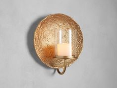 a candle is lit on the wall next to a round glass holder with a metal handle