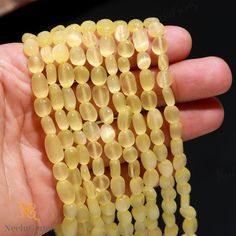 a hand holding some yellow beads in it's left hand on a black background