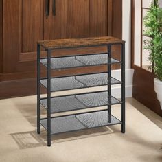 a shelf with three drawers in front of a wooden door and potted plant next to it