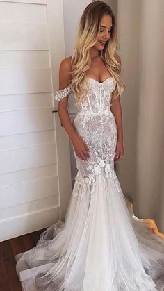 a woman in a white wedding dress standing on a wooden floor next to a door