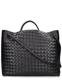 Find BOTTEGA VENETA Andiamo Leather Top Handle Bag on Editorialist. The BOTTEGA VENETA Andiamo Leather Top Handle Bag features a woven leather design, a top handle, and a detachable shoulder strap. It has a snap button closure, a front leather strap with a metal logo detail, and three internal pockets. The bag measures 35cm in height, 42cm in width, and 18cm in depth. The handle drop is 14cm, the strap drop when single is 44cm, and the strap drop when doubled is 23cm. It is a large tote bag that can be carried on the shoulder or hand carried. Formal Tote Shoulder Bag With Woven Leather, Formal Woven Leather Tote Shoulder Bag, Evening Woven Leather Handheld Bag, Formal Intrecciato Weave Shoulder Tote Bag, Evening Shoulder Bag With Double Handle In Woven Leather, Evening Shoulder Bag With Double Handle And Woven Leather, Black Bags With Intrecciato Weave, Evening Double Handle Woven Leather Shoulder Bag, Intrecciato Weave Shoulder Bag For Business