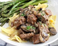 an easy beef and pasta dish with asparagus on the side in a white bowl