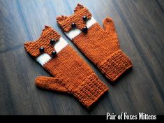 two knitted mittens sitting on top of a wooden floor