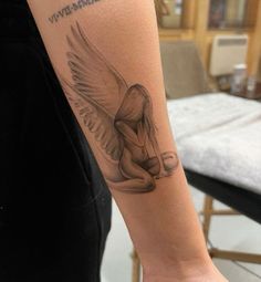 a woman's arm with a tattoo on it that has an angel sitting on her knees