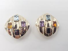 Title: Multicolor Gemstones Round Corner Square 14KT Yellow Gold Omega Clip Earrings Designer: Unbranded Material14KT Stamped Style: Vintage Gemstone Details All measurements are approximate and may vary slightly from the listed dimensions.1ar Approximately 5mm x 4mm each 1Amethyst Rectangular 1 Blue Topaz Rectangular 1 Orange Citrine Rectangular 1 Garnet Rectangular Estimated Measurements of the item30.23mm x 20.23mm x 5.83mm Estimated Total Weight of the Item DWT: 7.6 Grams: 11.7 Condition: Pr Multicolor Gemstone Accented Earrings For Formal Occasions, Luxury Multicolor Earrings For Evening, Formal Multicolor Earrings, Elegant Multicolor Gemstones For Anniversary, Luxury Multicolor Earrings For Formal Occasion, Luxury Gold Earrings With Stones, Multicolor Multi-stone Earrings For Anniversary, Formal Multicolor Gemstone Earrings, Multicolor Multi-stone Anniversary Earrings