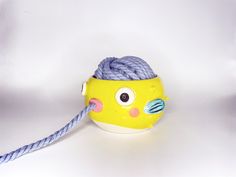 a yellow toy with a rope attached to it's side on a white surface