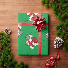 a present wrapped in green wrapping paper and tied with red ribbon, surrounded by christmas decorations