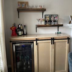 a small bar with bottles and glasses on the top shelf, next to a blue chair