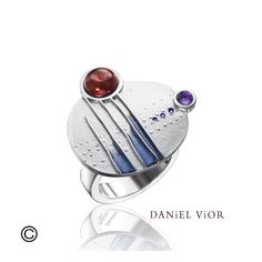 This intergalactic ring features a garnet and amethyst that are artfully bezel set and arranged on a flat medallion design, giving it a contemporary space-age look. Inspired by the beauty of asymmetry, raised lines and dots give this pretty ring added dimension, finished with streaks of colorful enamel.  This beautiful ring is made with a flat, square-edged band that allows it to lay comfortably when worn Modernist Round Cabochon Jewelry, Modern Amethyst Ring With Bezel Setting, Modern Multi-stone Rings, Modern Amethyst Ring As Gift, Modern Round Collectible Jewelry, Modern Sterling Silver Amethyst Ring, Contemporary Gemstone Rings For Gifts, Contemporary Gemstone Rings For Gift, Modern Amethyst Ring With Polished Finish