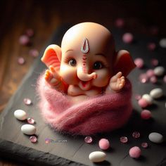 an elephant figurine sitting on top of a pink blanket covered in candies