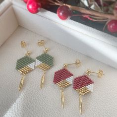 three pairs of beaded earrings on display in a white box next to christmas decorations