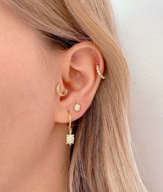 a woman wearing gold earrings with small white stones on the side of her ear,