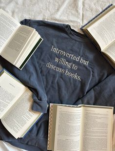 several open books laying next to each other on top of a blue shirt that says, uncovered but willing to discuss books