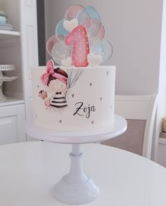 a white cake with pink and blue balloons on top