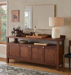 a living room with a table, mirror and vase on it's sideboard