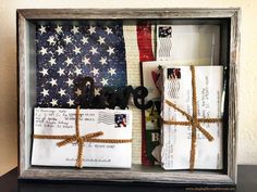 an american flag and some letters are in a shadow box that is decorated with twine