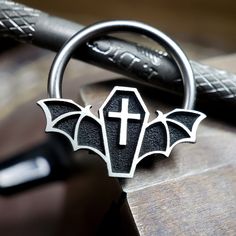 IMPORTANT (size & measuring guide): https://metallotus.com/blogs/body-jewelry/how-to-measure-your-piercing This 16 gauge niobium captive bead ring features a silver coffin bat captive bead design that measures approximately 14.3mm (wide) x 7.8mm (tall). It works well for septum, conch, helix and daith piercings. * The coffin bat bead design will take up approximately 5mm of the inner diameter when worn as septum or daith jewelry. * Each bead is carefully antiqued and then given a hand-brushed fi Gothic Septum Piercing, Gothic Septum Jewelry, Bats Art, Daith Piercings, Captive Bead Ring, Conch Piercings, Daith Jewelry, Helix Piercings, Septum Rings