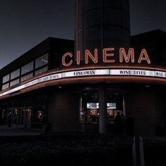 a movie theater with the word cinema lit up at night