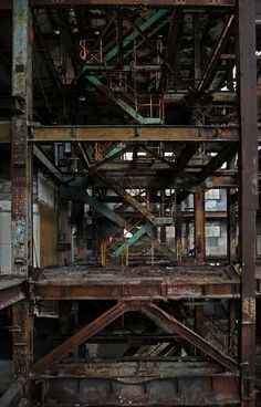 an old metal structure with lots of rust on the bottom and top floors, in a warehouse