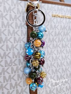 a keychain is hanging from the side of a purse with beads on it