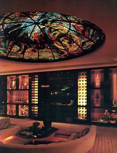 a living room filled with lots of furniture under a stained glass dome ceiling light fixture