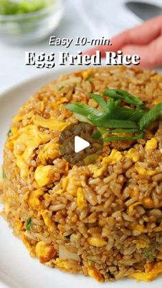 a white plate topped with fried rice and green beans next to a hand holding a fork