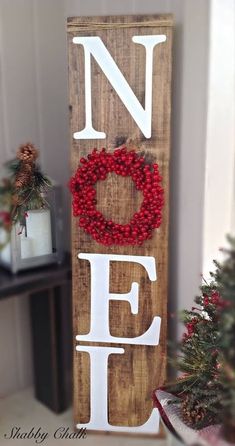 a wooden sign with the word noel spelled in white paint and decorated with red berries