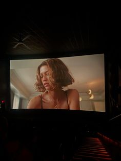 a large screen with a woman on it in the middle of a dark room,