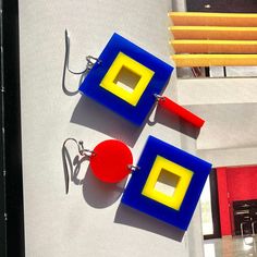 "These asymmetrical earrings are the graphic statement to make today.  The composition consists of embedded squares, circles, and small rectangle dangle in mismatched aesthetic.  Color combination is primary colors in blue, red, and yellow.  These designs are modern and playful -- the perfect accessory to liven up your style. Made from 1/8\" thick solid acrylic and have stainless steel hooks.    Earrings with circle on top:  Measurement is approximately 1-7/8\" long x 1-1/8\" wide. Earrings with dangle on the bottom:  Measurement is approximately 2\" long x 1-1/8\" wide. We draw, cut, and assemble each piece by hand.  Some small variations and imperfections are part of the process which make each item unique! Made in Los Angeles, California. Visit our website: www.getmadeinla.com Join us o Bold Geometric Earrings With Bold Design, Bold Geometric Designed Earrings, Modern Square Single Earring, Bold Geometric Earrings, Modern Geometric Blue Jewelry, Modern Blue Geometric Jewelry, Bold Handmade Geometric Earrings, Modern Handmade Geometric Earrings, Handmade Modern Geometric Earrings