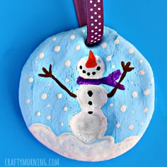 a painted snowman ornament hanging on a blue background