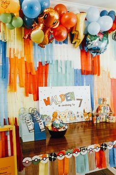 a birthday party with balloons and streamers on the wall, along with an assortment of items