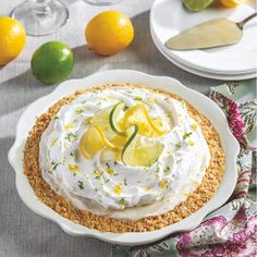 there is a pie with lemons and whipped cream on the top, next to some limes