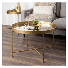 two tables sitting on top of a wooden floor next to a couch