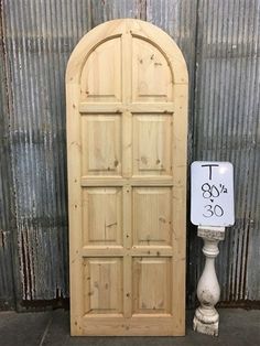 an arched wooden door next to a sign