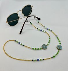 Whether you're headed to a festival, taking a stroll along the beach, or just walking around the block, these sunglass chains are both handy and stylish to bring along for the ride. Convenient if you want to let your glasses hang comfortably on your chest, or put them on to add some flair to any activity you're getting into. Elastic endpieces stretch out and make it easy to slide the chain onto any pair of sunglasses or reading glasses. Each pair is handmade with love in colorful Colorado :) Custom designs are welcome, let me know what you have in mind and I'd love to make it happen! **Photos 3 & 4 are just examples of what they look like on, not necessarily the exact same pair you're looking at. Bohemian Sunglasses With Uv Protection For Vacation, Green Sunglasses For Beach, Blue Sunglasses For Summer Travel, Summer Beach Sunglasses With Glass Material, Summer Beach Sunglasses With Glass Lenses, Summer Fashion Sunglasses With Tinted Lenses, Summer Tinted Sunglasses, Blue Beaded Glasses Chain For Beach, Multicolor Glass Sunglasses For Festivals