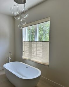 a white bath tub sitting under a window in a bathroom