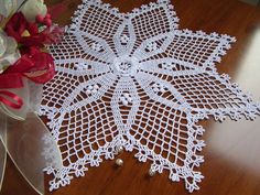 two white doily sitting on top of a wooden table next to a bouquet of flowers