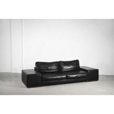 a black leather couch sitting on top of a white floor