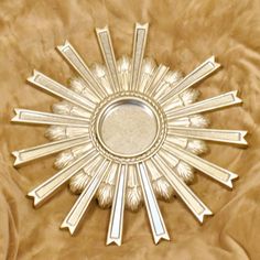 a sunburst shaped mirror sitting on top of a tan cloth covered bed sheet