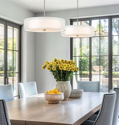 a dining room table with yellow flowers in a vase on it and blue chairs around the table