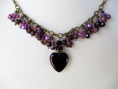 Purple Beaded Cluster Necklace Made with a purple glass heart pendant, mixed glass beads/seed beads, brass beads, toggle clasp, and chain. All dangles are handmade. 17" in length with extender chain to 18". This bold Purple Beaded Cluster Necklace ships to you in a gift box, ready to give as a present or to keep and store. Back to Necklaces Purple Heart-shaped Jewelry With Colorful Beads, Purple Heart Jewelry With Colorful Beads, Purple Czech Glass Beaded Necklace For Gift, Purple Heart-shaped Beaded Jewelry, Purple Heart Beads Necklace For Gift, Bohemian Purple Necklace With Heart Beads, Gift Czech Glass Heart Beaded Necklaces, Purple Round Beads Jewelry For Valentine's Day, Purple Round Bead Jewelry For Valentine's Day