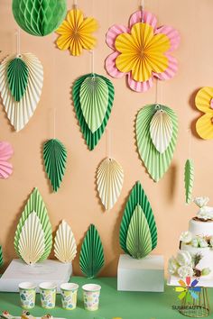 paper fans hanging on the wall next to cupcakes and dessert cups in front of them