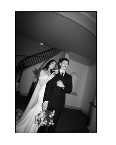 a man and woman standing next to each other in front of a stair case with flowers on it