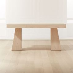 a wooden table sitting on top of a hard wood floor next to a white wall