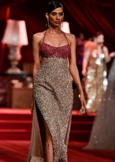 a model walks down the runway in a dress with high slits and beading