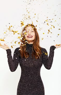 a woman with confetti all over her face and hands in front of her head