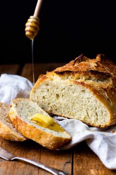 a loaf of bread sitting on top of a wooden table next to a honey stick