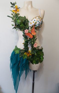 a mannequin with flowers and leaves on it's torso is shown in front of a white wall