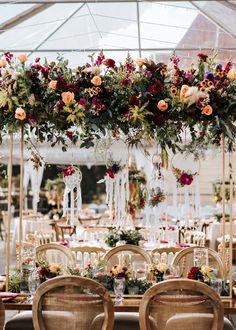 a table with chairs and flowers hanging from it's ceiling in front of a tent