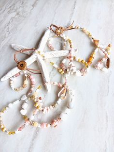 Two options of this sweet, soft, flirty, and beachy ribbon of color. Extra long at 36". Great texture and interest...soothing pinks, yellow, apricot, caramel, beige, blush, white, and sandy hues. These pieces includes quality Pearls, Citrine, Agate, Jade, Jasper, several pearls, Mother of Pearl, Opal, Sunstone, Aventurine, and more. Unique sea shells, shell disks, seed beads, and more. Unique bone or wood button and natural suede closure, extendable. Strung on Beadalon 7 strand wire-great streng Whimsical Pink Jewelry For Beach, Whimsical Pink Beach Jewelry, Pink Strand Necklaces For Summer, Summer Pink Strand Necklaces, Pink Beach Necklace For Summer, Pink Strand Necklaces For Vacation, Pink Strand Beachy Jewelry, Handmade Pink Jewelry For Beach, Summer Beach Pink Necklace